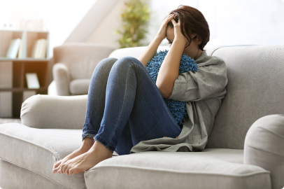 Woman on a couch with her head in her hands needing online counseling for depression